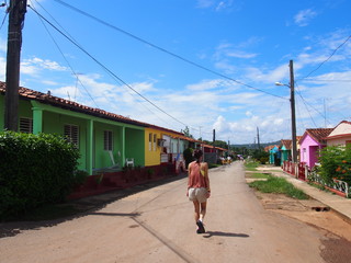 A woman walking down the street lined with pretty colored houses, Vinales, Cuba