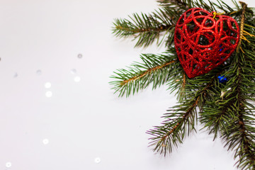 Green spruce branch with glitter decorations in the corner close up on white background
