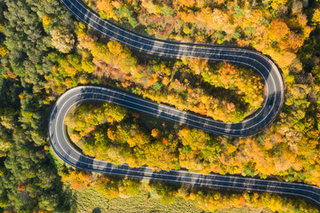 Beautiful aerial landscape of mountain forest road. Aerial view of curvy road in beautiful autumn forest
