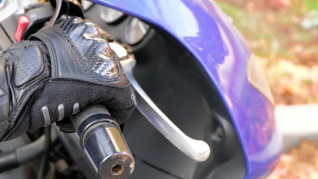 Close up shot of man in gloves holding twist grip throttle and revving the engine. Starting motorcycle