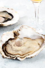 A large oyster, fresh and raw, a close-up shot with ice and the stem of a wineglass