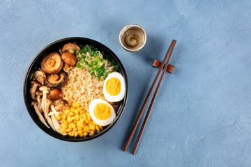Ramen. Soba noodles with boiled eggs, shiitake mushrooms, and vegetables, shot from the top with chopsticks, sake, and a place for text