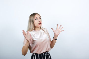 Portrait of scared young woman in casual clothes looking up, rising hands, like shocked isolated on white background. People sincere emotions, lifestyle concept