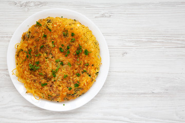 Homemade spaghetti omelette on a white plate over white wooden surface, overhead view. Flat lay, top view, from above.