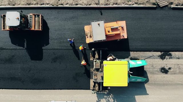 Workers and industrial machines are spreading bitum
