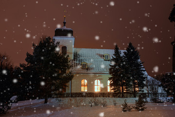 Fototapeta premium Christmas time, winter landscape, church in the evening in snowy weather, lit by lights