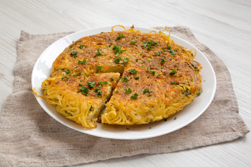 Homemade spaghetti omelette on a white plate, side view. Close-up.