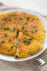 Homemade spaghetti omelette on a white plate, low angle view. Closeup.