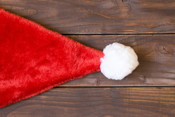 Obraz na płótnie Canvas Christmas card idea, santa hat on a wooden background with copy space