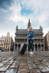 Obraz premium Woman tourist goes with a suitcase at the Grand Place in Brussels, Belgium