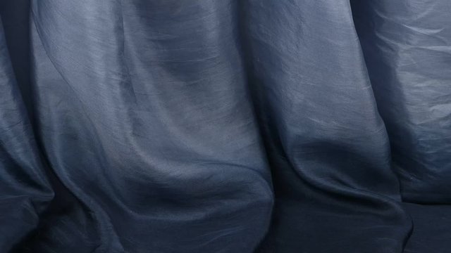 Dark gray and crushed silk fabric is draped with vertical soft pleats, background