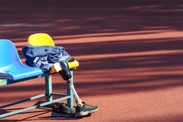 Prosthetic leg, sneakers and jacket on a seat at the stadium.
