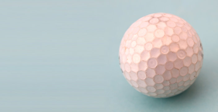 The golf ball is dirty on the blue background with copy space.