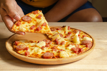 pizza slice in hand.Pizza is a savory dish of Italian origin, consisting of a usually round, flattened base of leavened wheat-based dough topped.