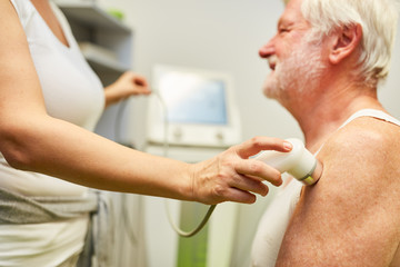 Female doctor treats senior patient with ultrasound