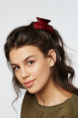 Closeup half-turn face portrait of girl with dark wavy hair, wearing khaki t-shirt. Her hair is...