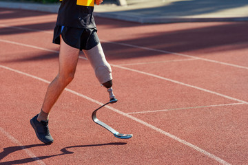 Low-section portrait of amputee sportsman. Athlete running on a track