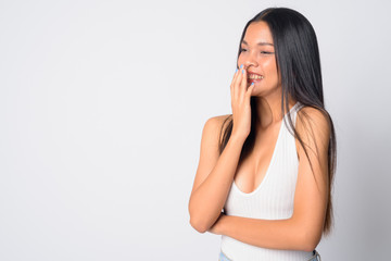 Fototapeta premium Portrait of happy young beautiful Asian woman laughing and covering mouth