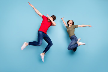 Fototapeta na wymiar Full size photo of funky crazy two married people students fun jump man perform dab dancers woman raise hands wear green red t-shirt denim jeans sneakers isolated blue color background