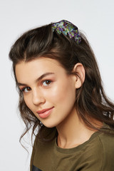 Closeup half-turn face portrait of girl with dark wavy hair, wearing khaki t-shirt. Her hair is...