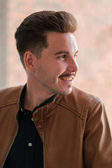 Obraz premium portrait of a young guy in a black shirt and brown leather jacket. casual style