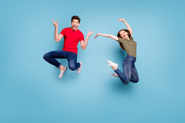 Fototapeta na wymiar Full length photo of cheerful two people students man heavy metal lover show horns woman jump raise hands wear green red t-shirt denim jeans isolated blue color background