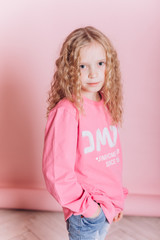 Close up portrait of young cute adorable caucasian kid on soft pink background indoors in studio. Positive concept, childhood happiness concept.