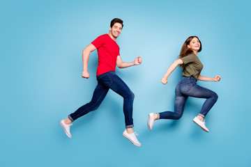 Fototapeta na wymiar Full size profile side photo of cheerful romantic married people jump run after spring discounts wear green red t-shirt denim jeans sneakers isolated over blue color background