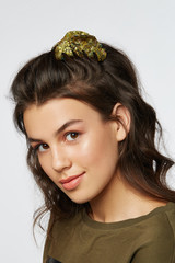 Closeup half-turn face portrait of girl with dark wavy hair, wearing khaki t-shirt. Her hair is...