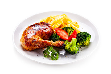 Grilled chicken leg with chips and vegetables on white background