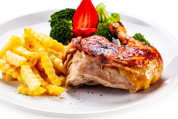 Grilled chicken leg with chips and vegetables on white background
