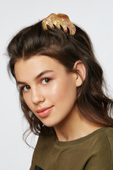 Closeup half-turn face portrait of girl with dark wavy hair, wearing khaki t-shirt. Her hair is...