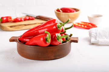 Fresh ripe red pepper in ceramic bowl on white table.