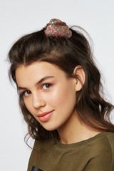 Closeup half-turn face portrait of girl with dark wavy hair, wearing khaki t-shirt. Her hair is...