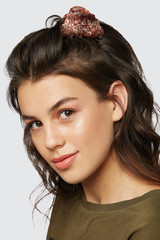 Closeup half-turn face portrait of girl with dark wavy hair, wearing khaki t-shirt. Her hair is...