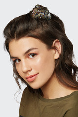 Closeup half-turn face portrait of girl with dark wavy hair, wearing khaki t-shirt. Her hair is...