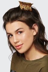 Closeup half-turn face portrait of girl with dark wavy hair, wearing khaki t-shirt. Her hair is...
