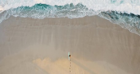 Aerial view of a woman on the beach going surfing - Powered by Adobe