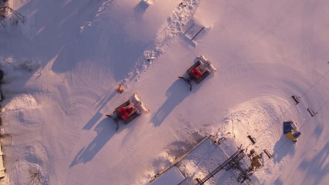 Top Shot Drohne einer Skipiste die fr&uuml;h morgens bei morgenr&ouml;te von pistenbullies aufbereitet wird,