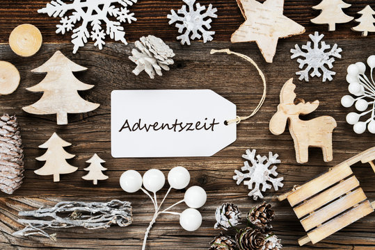 One White Label With German Text Adventszeit Means Advent Season. Frame Of Christmas Decoration Like Tree, Sled, Star And Fir Cone. Wooden Background