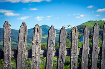 Weathered Timber Picket Fence in the Mountain Village on a Sunny Summer Day. Altai Mountains, Kazakhstan.