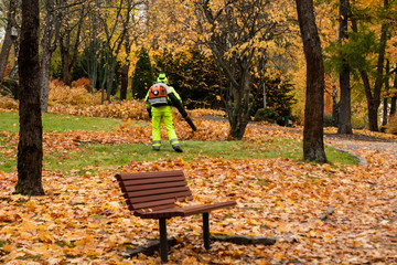Worker in autumn park with a leaf blower