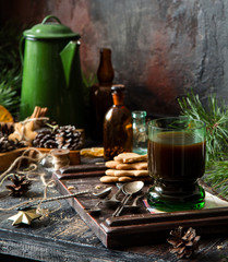 christmas coffee in green glass on rustic wooden table with gingerbread cookies, fir tree branches