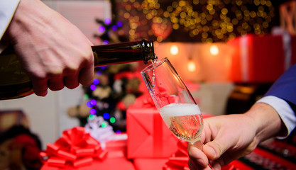 Drink champagne or sparkling wine. Celebrate new year with champagne. Hands pouring champagne into elegant glass christmas decorations background. Cheers concept. Last minute before new year