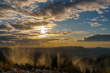Sunset panorama in the Black Forest Mountains at golden hour with some fog and cloudy sky