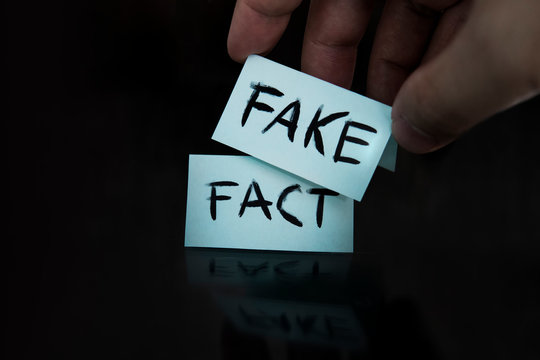 The fact is replaced by a fake. substitution of concepts. a man changes the signs with the words fact on fake on a black background.