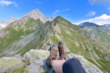 foot and legs of a hiker sitting at the top of  alpine mountain