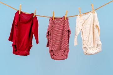 Baby girl clothes pinned on a clothesline against blue background