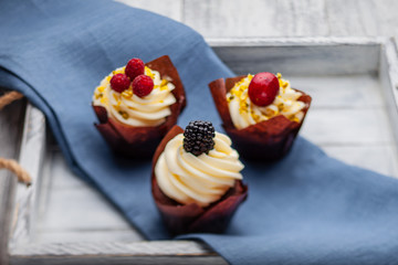 muffins with Belgian chocolate and white chocolate cream and mascarpone with berries on a wooden tray