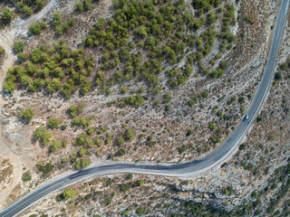 The car rides on a winding mountain road. Top down aerial view